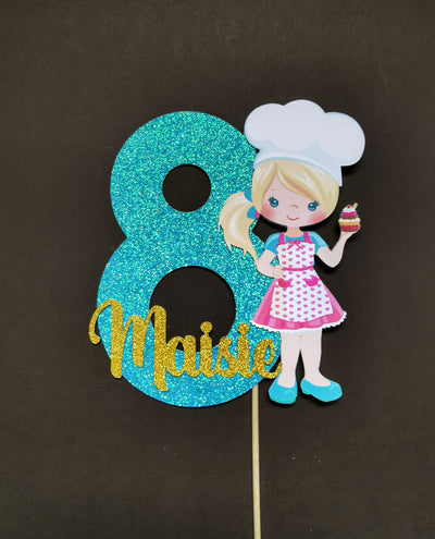 cake topper with a baker character holding a cupcake on a dark background