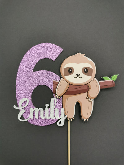 Cake topper with a sloth and number 6 on a stick against a dark background