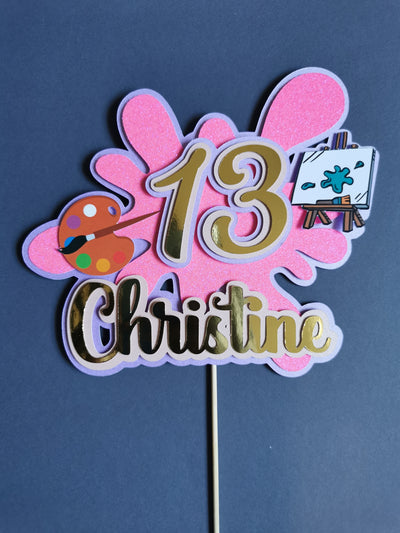Art themed cake topper with name and age on a blue background