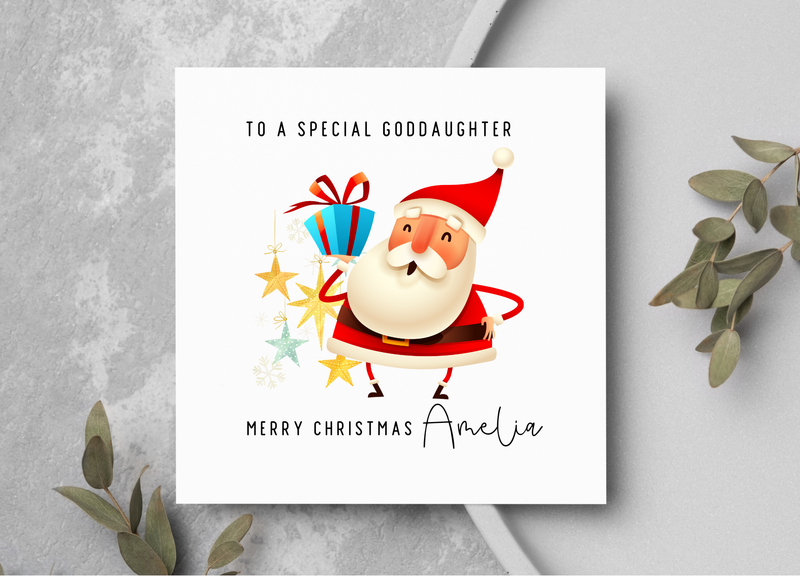 Christmas card with Santa Claus holding presents on a gray surface with greenery.