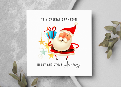 Christmas card with Santa Claus holding presents on a gray surface with greenery.