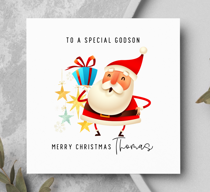 Christmas card with Santa Claus holding gifts on a gray surface with greenery.