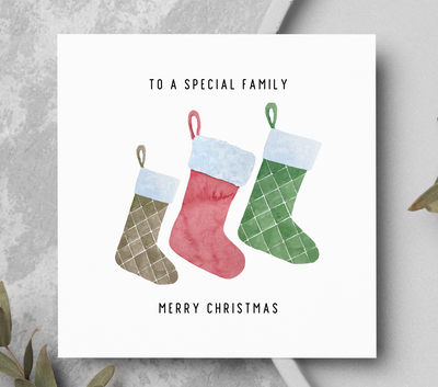Christmas card with stockings and text 'To a special family, Merry Christmas' on a gray surface.