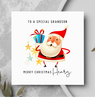 Christmas card with Santa Claus holding presents on a gray surface with greenery.