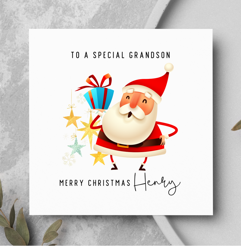 Christmas card with Santa Claus holding presents on a gray surface with greenery.